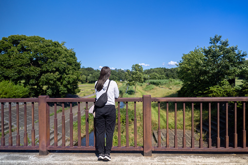 Female hiker looking at view from bridge in public park