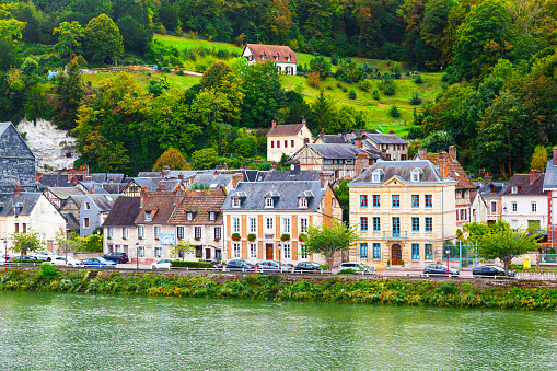 The coast of the Seine River in France in the suburbs of Rouen with beautiful private houses and dense green vegetation and mountains.