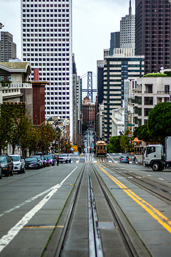 View of the Bay Bridge from the hills of San Francisco, California, with a cable car on the street