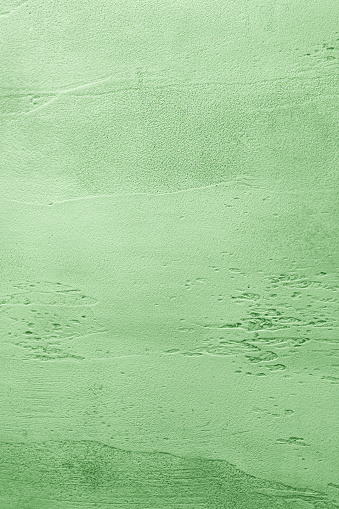 Green textured concrete background with light base darker in the recesses. Abstract texture for graphic design or wallpaper, top view.