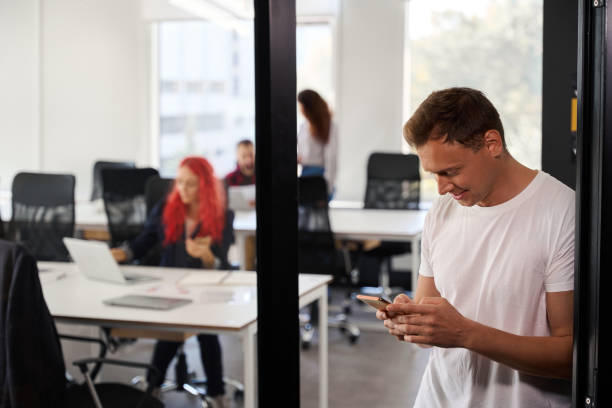 istock Smiling man in white t-shirt chatting on smartphone instead of work 1923544632