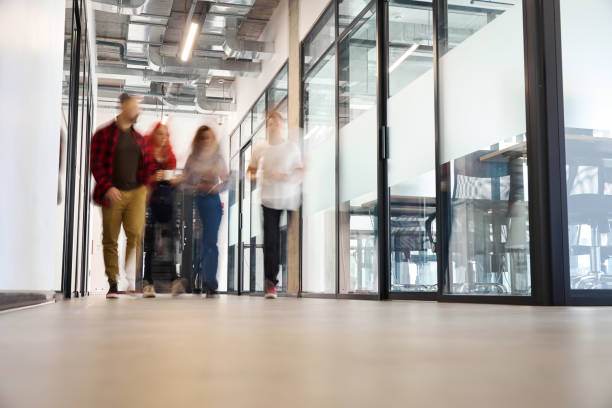istock Blurred view people walking along bright office hall with big panoramic windows 1923544678