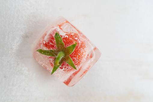 Photographic documentation of some small tomatoes inside an ice cube