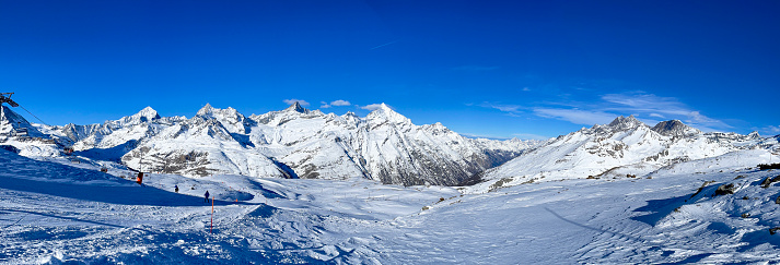 Beautiful winter scenery with trees and mountain tops in the Alps on a sunny day with blue sky and clouds.
