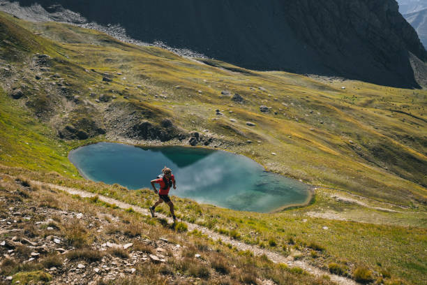 istock Trail runner bounds along mountain trail above lake 1923641465