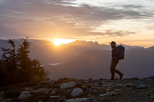 Backpacker explores mountain ridge in alpine environment at sunset
