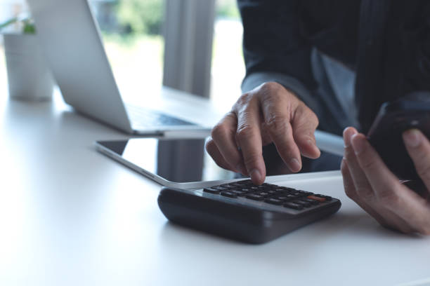 istock Business man using calculator to calculate business report, e-document on mobile phone and digital tablet, working at modern office 1923696966