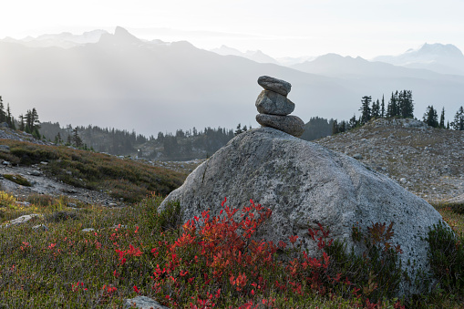 Stack of rocks on boulder in mountain meadow at sunrise