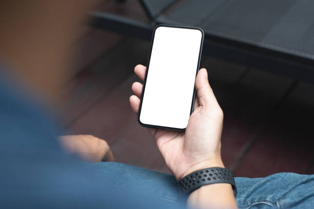 Mobile phone mockup for advetising. Mock up image of man hand holding and using smartphone with blank screen for mobile app design or text advertisement Mobile phone mockup for advetising. Mock up image of man hand holding and using smartphone with blank screen for mobile app design or text advertisement, people lifestyle man looking at phone over shoulder stock pictures, royalty-free photos & images
