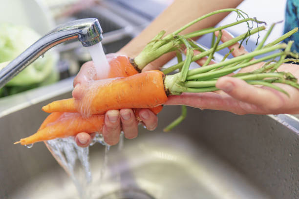 istock Woman hands washing fresh orange carrots in a kitchen 1923751149