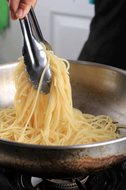 istock Selected Focus Close Up Take Out  Boiled Spaghetti  Pasta from the Pan with Stainless Tongs, Cooking Process in the Kitchen 1923777321