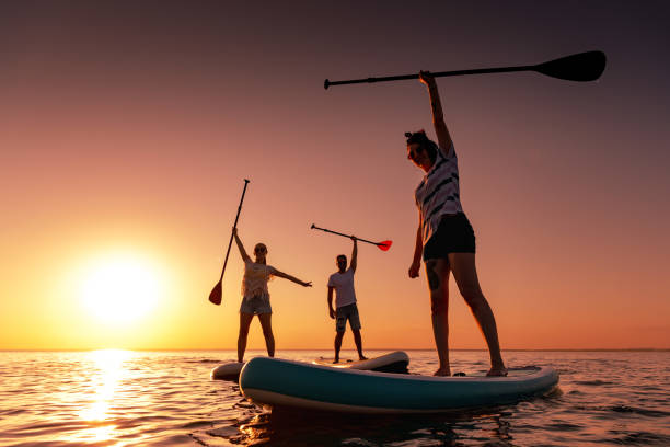 istock Three happy friends are paddleboarding on sups at sunset 1923783591