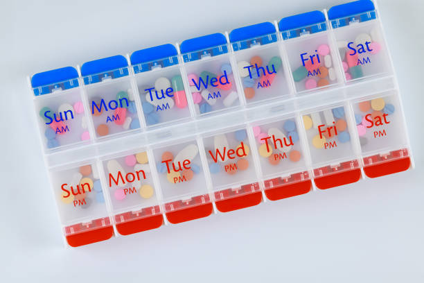 an organizer box with medication capsules on a white background - vitamin pill capsule equipment data imagens e fotografias de stock