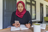 Asian Muslim Woman Calculating Her Investment Return on Cryptocurrency