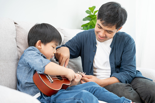 Happy single father playing learning music with the little boy. Funny family is happy and excited in the house. Father and son having fun spending time together. Vacant time, holiday