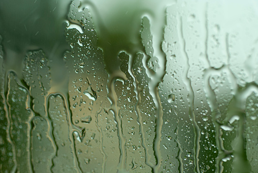 Rainy city background. Raindrops on window glass on autumn day. Wet home window with raindrops. High quality photo.