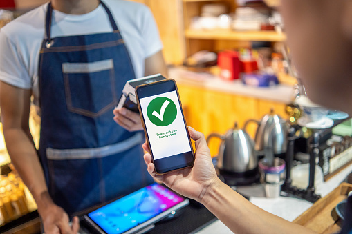 Contactless payment concept, female customer holding smart phone near nfc technology on counter