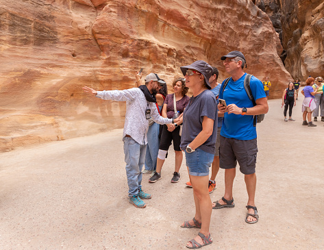 Wadi Musa, Jordan, October 05, 2023 : A local guide tells tourists about the gorge Al Siq in Petra in Wadi Musa city in Jordan