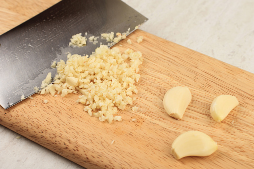 Chopping Garlic on Wooden Board suing Sharp Knife