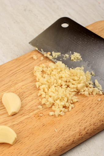 Chopping Garlic on Wooden Board suing Sharp Knife