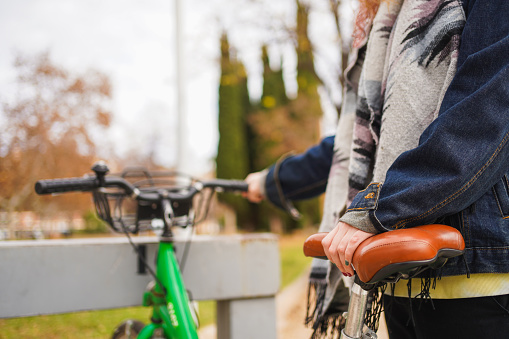 Portrait of teenage student girl with backpack on bicycle. Smiling teen female 16, 17 years old looking at camera outdoors on road. High school, lifestyle, adolescence, youth concept