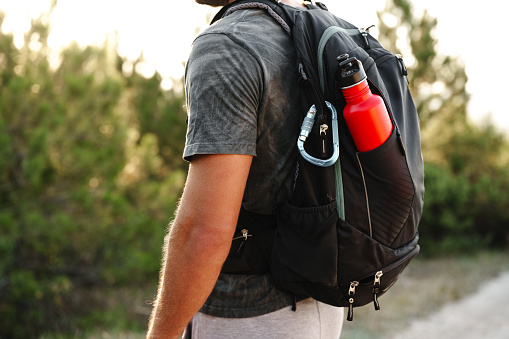 A male traveler backpack with mountaineering carabiner and thermos close up back view