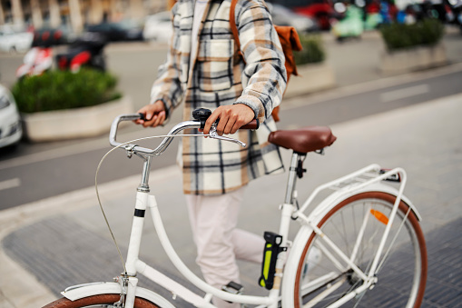 An unknown hipster is using rent a bike during his visit to a Europe city.