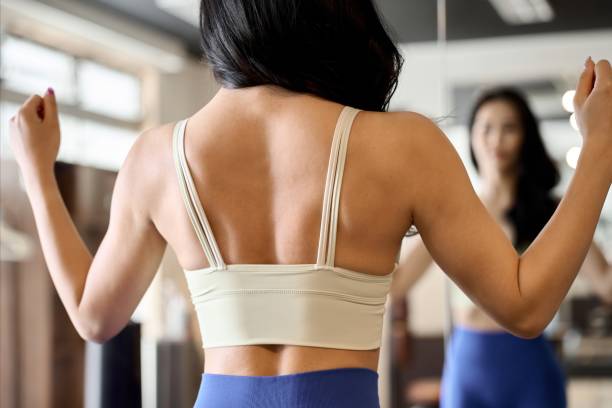 Woman posing in front of a gym mirror Woman posing in front of a gym mirror scapula stock pictures, royalty-free photos & images