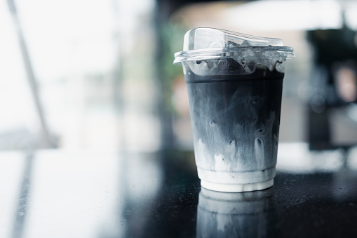 Ice charcoal latte with fresh milk it showing the texture and refreshing look of the drink in plastic cup