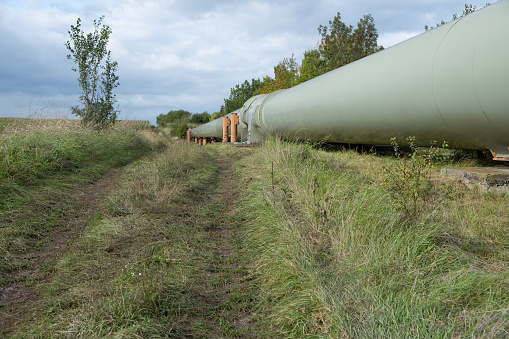 A colossal tube represents a thermal energy transfer infrastructure, central heating pipes enveloped in a robust metal thermal insulation jacket. Above-ground in European regions distribution and energy transportation.