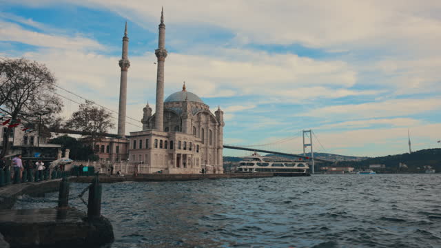 SLO MO Handheld Shot of Ortakoy Mosque and Bosphorus Bridge by Sea against Cloudy Sky at Istanbul,Turkey