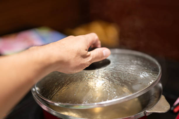 Action of people hand is preparing to open the Sukiyaki or Shabu Shabu pottery's lid after water already boiled. Selective focus photo.
