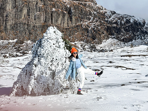 A woman traveling in cold weather in snow-covered mountains and trees