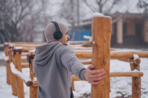 Athletic young man doing warming up before his  workout in snowy park