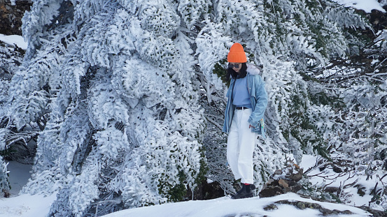 A woman traveling in cold weather in snow-covered mountains and trees