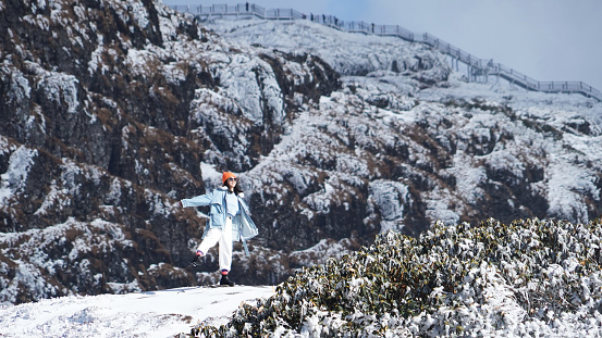 A woman traveling in cold weather in snow-covered mountains and trees
