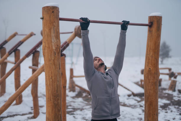 istock Strong young man doing pull-ups on outdoor bar while training at workout area in winter 1924179635