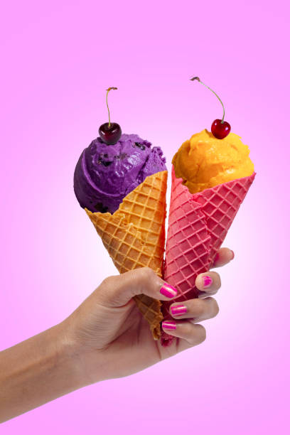 istock Woman's hand holding Blackcurrant and mango ice cream cone. Two ice cream cone in hand. 1924200467