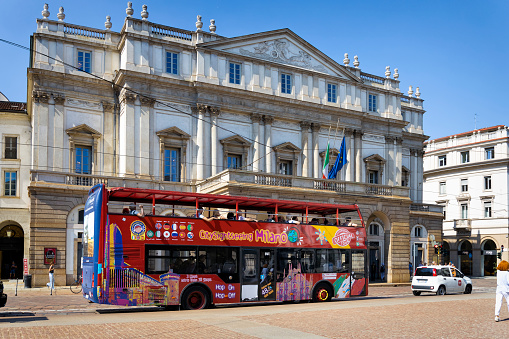 Open Tour double decker bus  with tourists near La Scala theatre in Milan, Italy