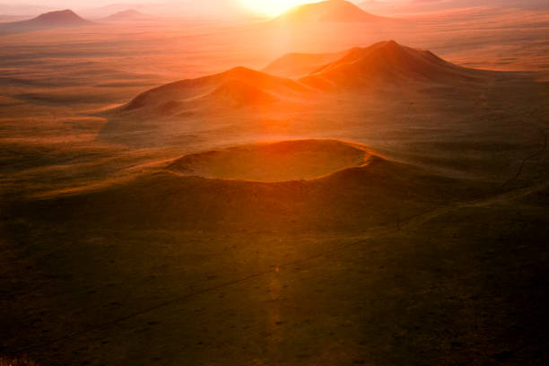 cratere vulcanico nella steppa della mongolia nella retroilluminazione arancione del sole che sta al tramonto o nascente all'orizzonte - crateri foto e immagini stock