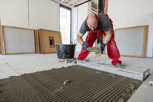 Blue collar worker spreading tile adhesive