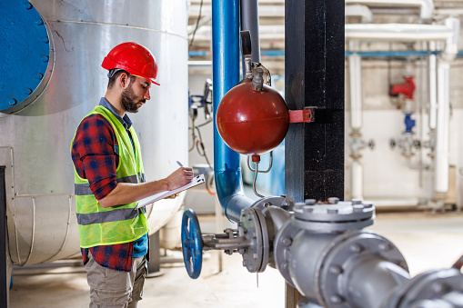 This image showcases a young man in a heating plant updating files to ensure that all data is accurate and up-to-date