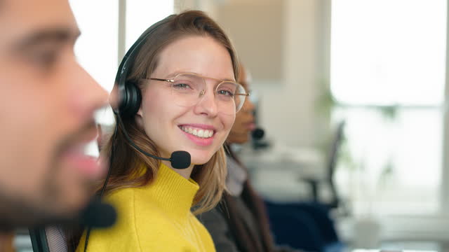 Friendly woman working in a call center with colleagues sitting by