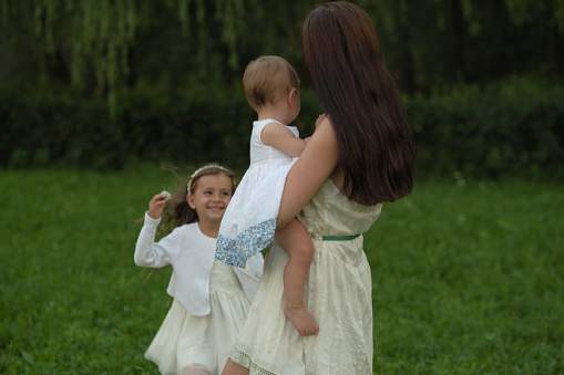 Amidst a field of flowers, a woman shares a moment of affection with her children, a testament to the nurturing spirit of family. Their connection reflects the natural instinct of care and guidance