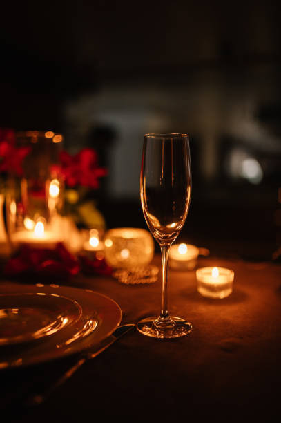 candlelight date in restaurant. champagne glasses, bouquet flowers. romantic dinner setup at night. table setting for couple, valentine's day evening, burning candles for surprise marriage proposal. - champagne wedding luxury dinner foto e immagini stock