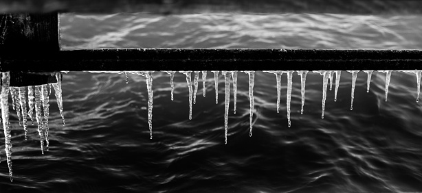 A row of icicles. Black and white photography.