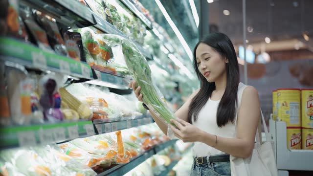 Asian woman choosing vegetables at the grocery store