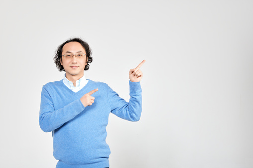 Portrait of a positive man pointing finger and smiling isolated on white