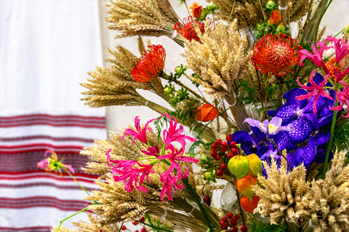 Floral arrangement of dry bunches of wheat and flowers in folk style