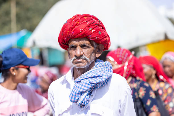 Pushkar, Rajasthan, India - November 2022: Pushkar fair, Portrait of an rajasthani old male with in white traditional dress and colorful turban at pushkar fair ground.